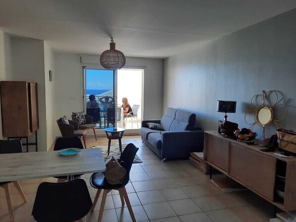 A modern living room with a dining area, a sofa, a coffee table, and a TV on a wooden cabinet.