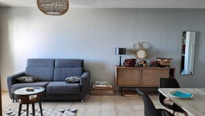 A living room with a sofa, coffee table, and a dining area with a table and chairs. - Comfortable T3 with terrace 5 minutes walk from Saint-Leu beach (Saint-Leu)