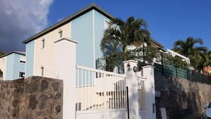 A two-story building with a stone wall and a gated entrance. - Comfortable T3 with terrace 5 minutes walk from Saint-Leu beach (Saint-Leu)
