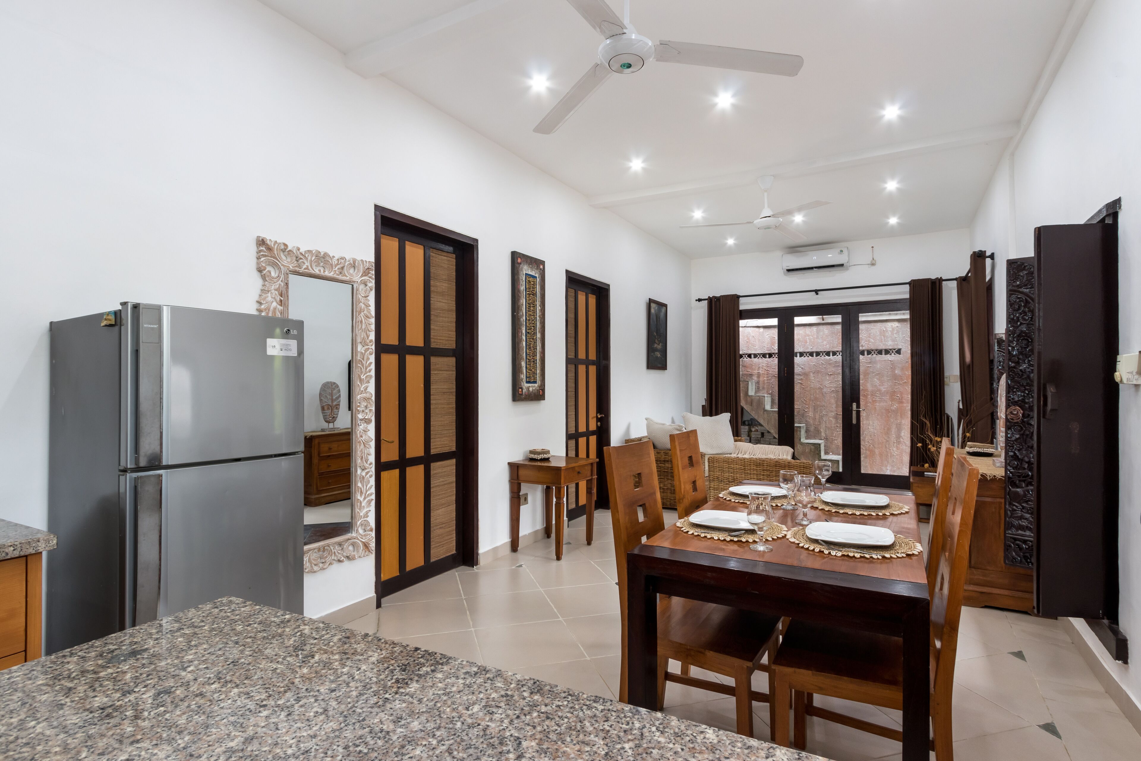 Comedor con encimera de granito, sillas de madera, mesa puesta para cuatro y ventilador de techo.