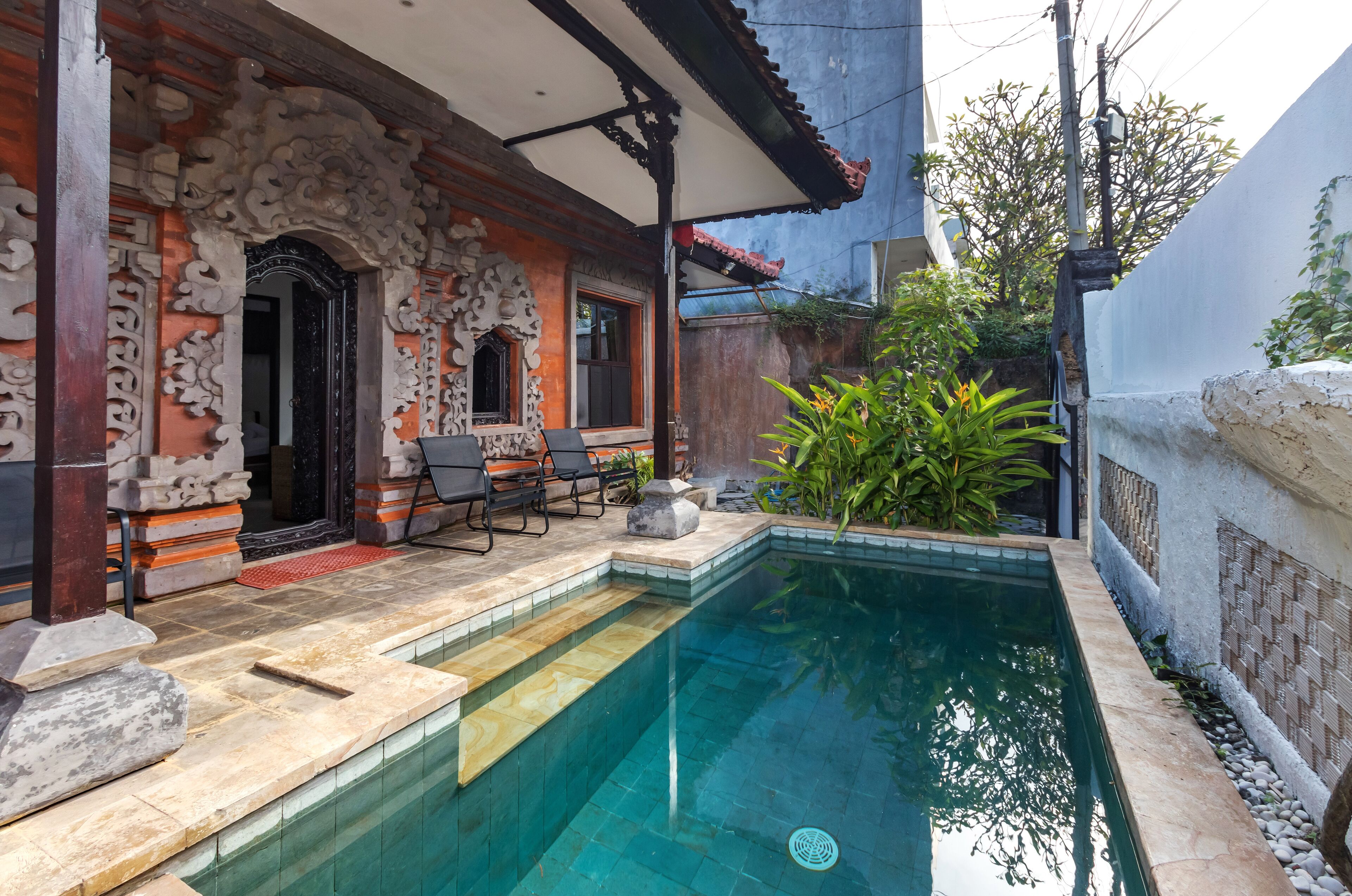 A traditional house with a swimming pool, outdoor seating, and a decorative entrance.