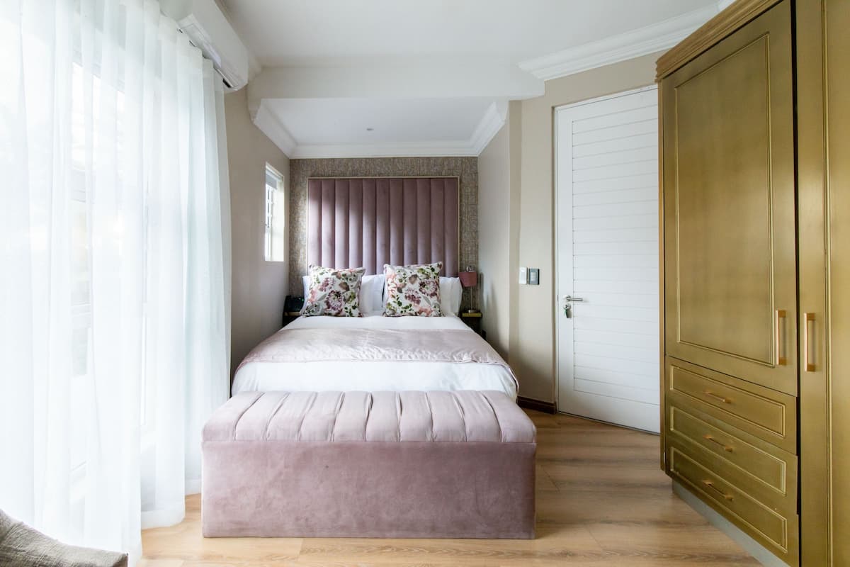Een slaapkamer met een bed, een grote kledingkast en een raam met gordijnen.