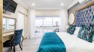 Un dormitorio con una cama grande, un escritorio y vista al mar a través de una puerta corredera.