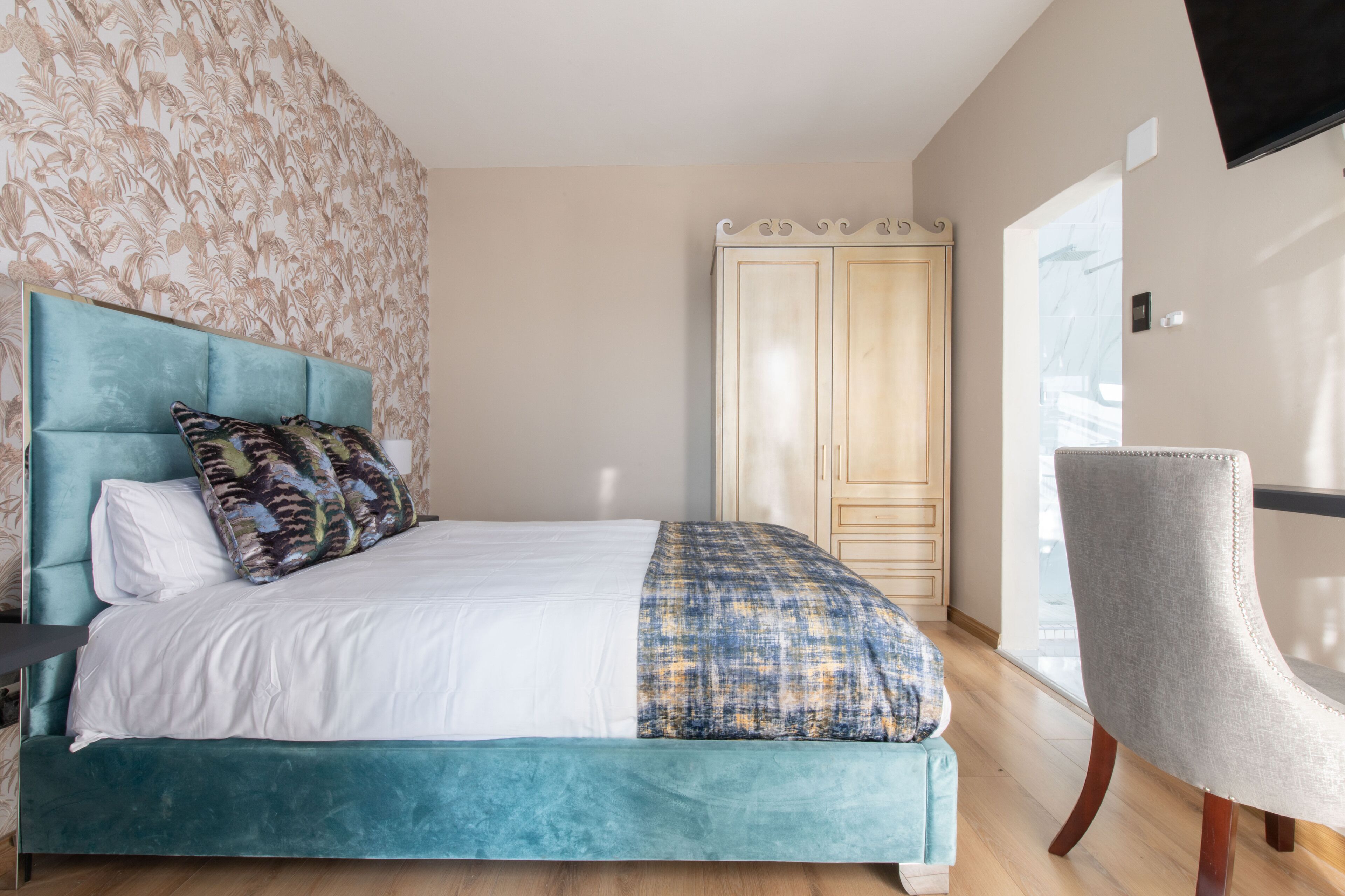 A bedroom with a bed, a chair, and a wardrobe.