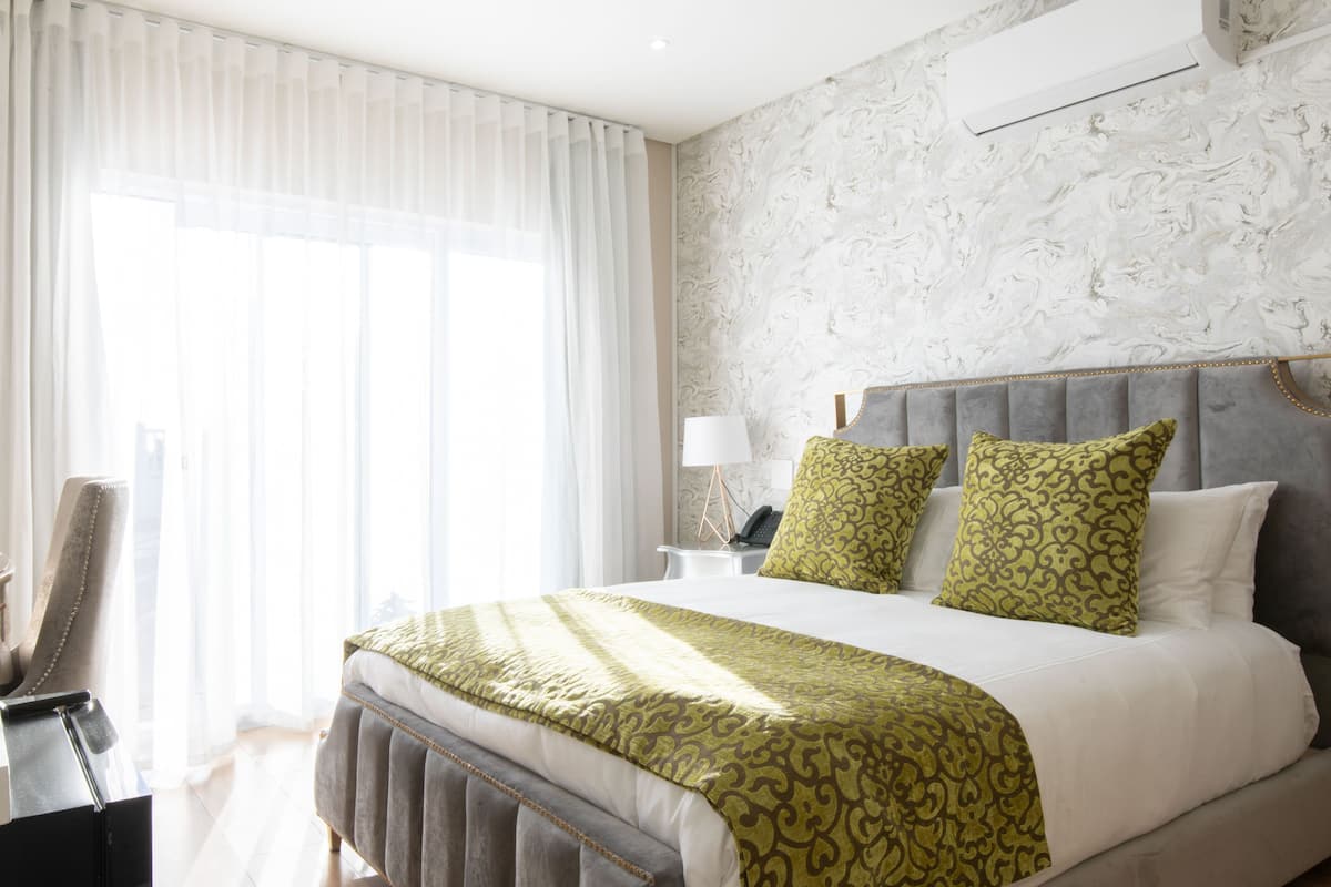 Een hotelkamer met een groot bed, een nachtkastje met een lamp en een stoel.