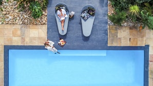 Luftaufnahme eines Poolbereichs mit Liegestühlen und einer gefliesten Terrasse.