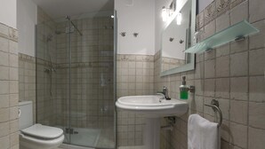 Ein Badezimmer mit Duschkabine, Standwaschbecken, Toilette und Handtuchhalter.