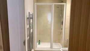 A modern bathroom with a glass shower enclosure, a built-in toilet, and a towel rack. - Large Private Flat in City Centre Leeds (Leeds)