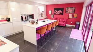 Une cuisine moderne avec un îlot central, des tabourets de bar, un canapé rose et une table à manger.