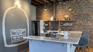 Una cocina moderna con una isla grande, pared de ladrillo y lámparas colgantes.