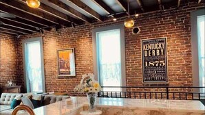 Una cocina moderna con encimera de mármol, un jarrón de flores y una pared de ladrillo con un cartel del Kentucky Derby.