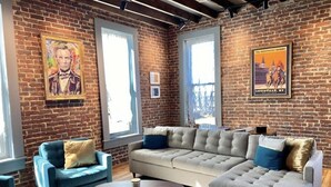 Una sala de estar moderna con una pared de ladrillo, un sofá modular, un sillón azul y una mesita de centro.
