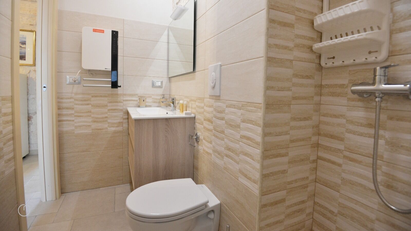 Casa de banho compacta com sanita, lavatório e chuveiro.
