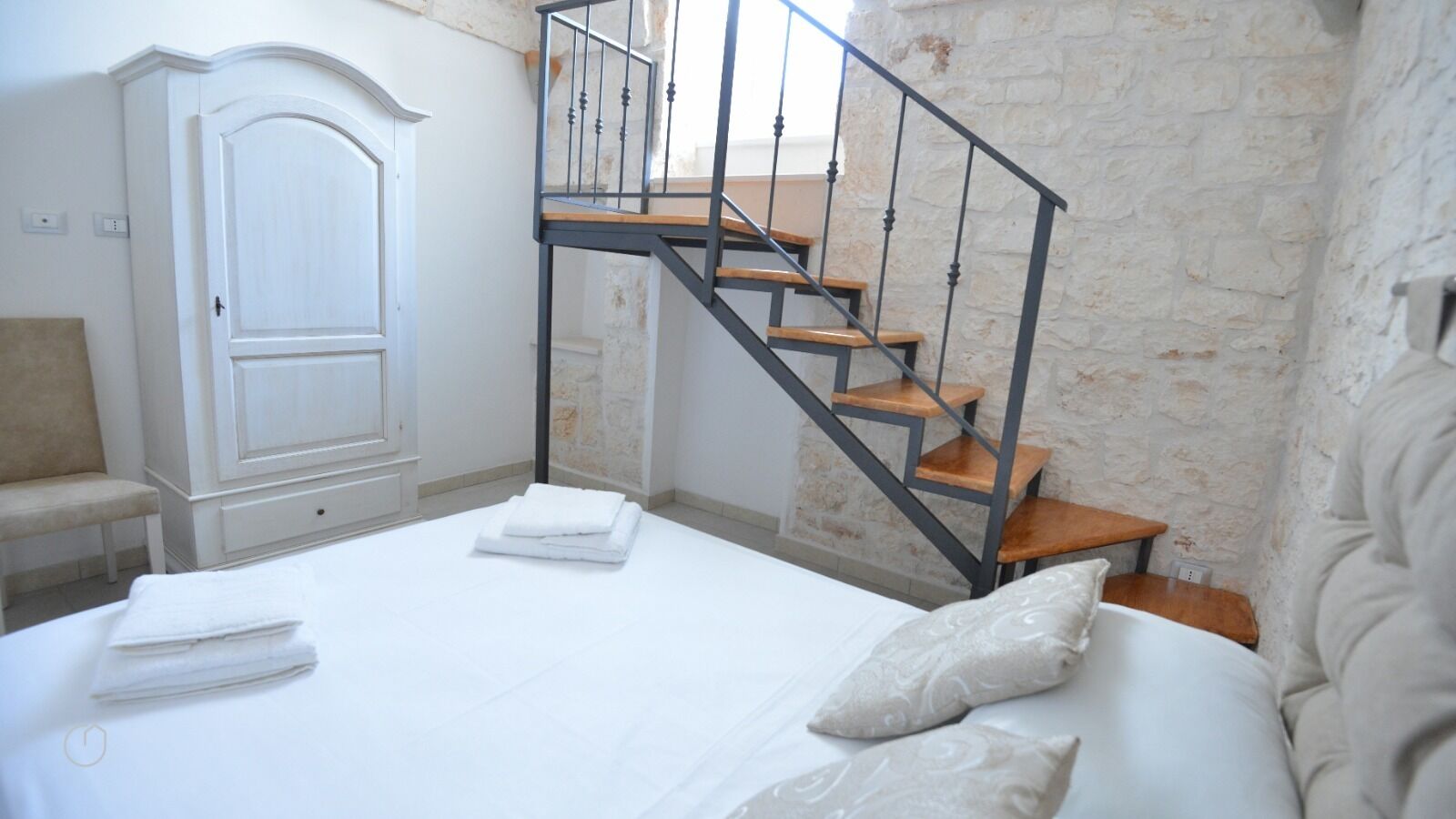 Un dormitorio con cama, una silla, un armario y una escalera.
