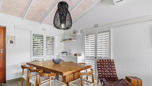 A dining area with a wooden table and chairs, a woven chair, and a woven bench. - San Lameer Villa 2533 (Southbroom)