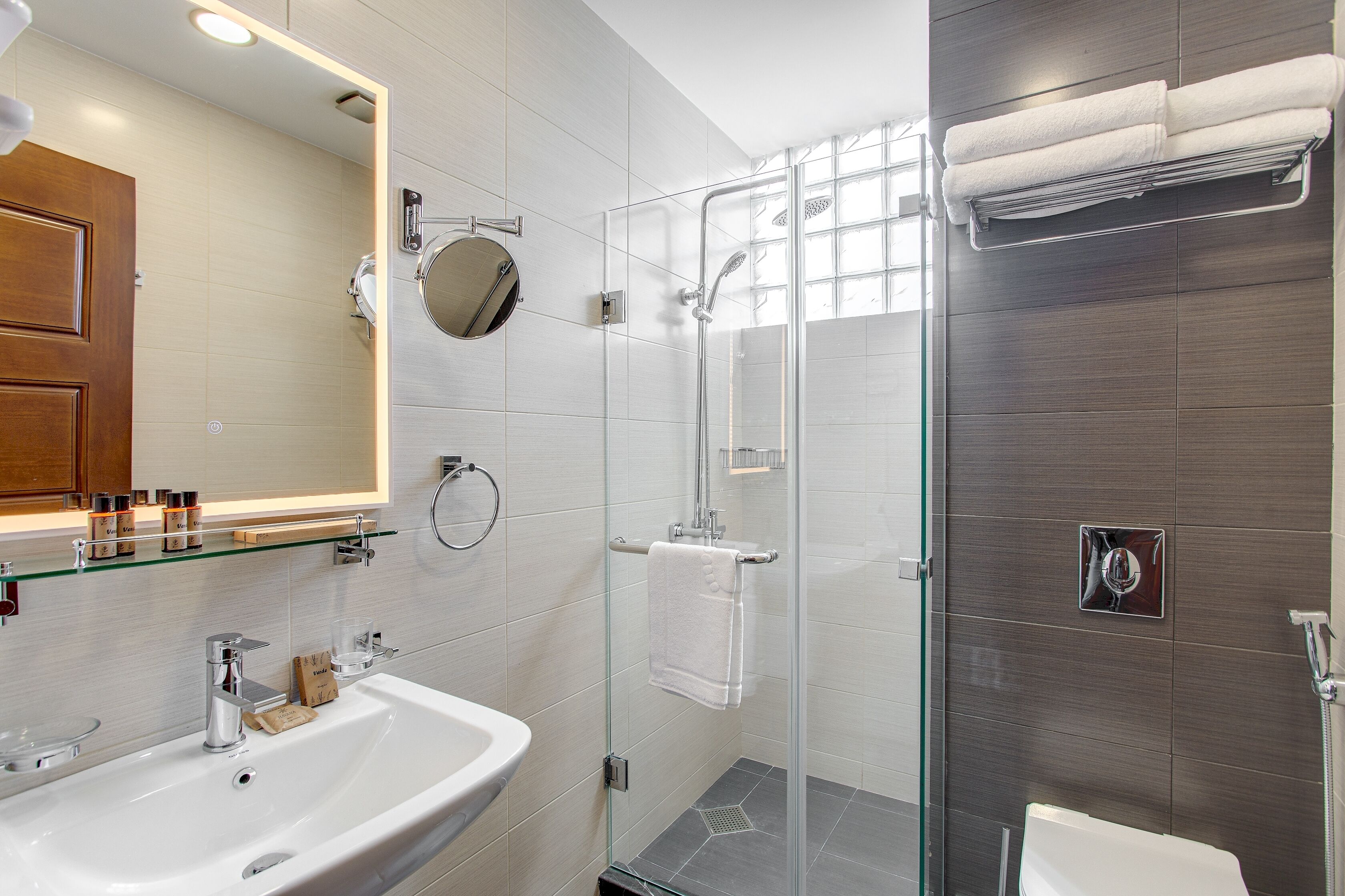 Une salle de bain moderne avec une douche à parois de verre, un lavabo blanc et un grand miroir.