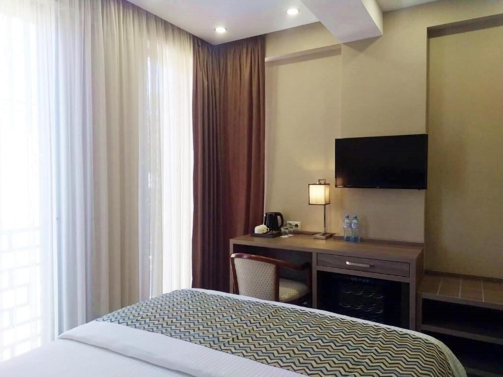 Une chambre d’hôtel équipée d’un lit, d’un bureau, d’une télévision et d’un mini-bar.