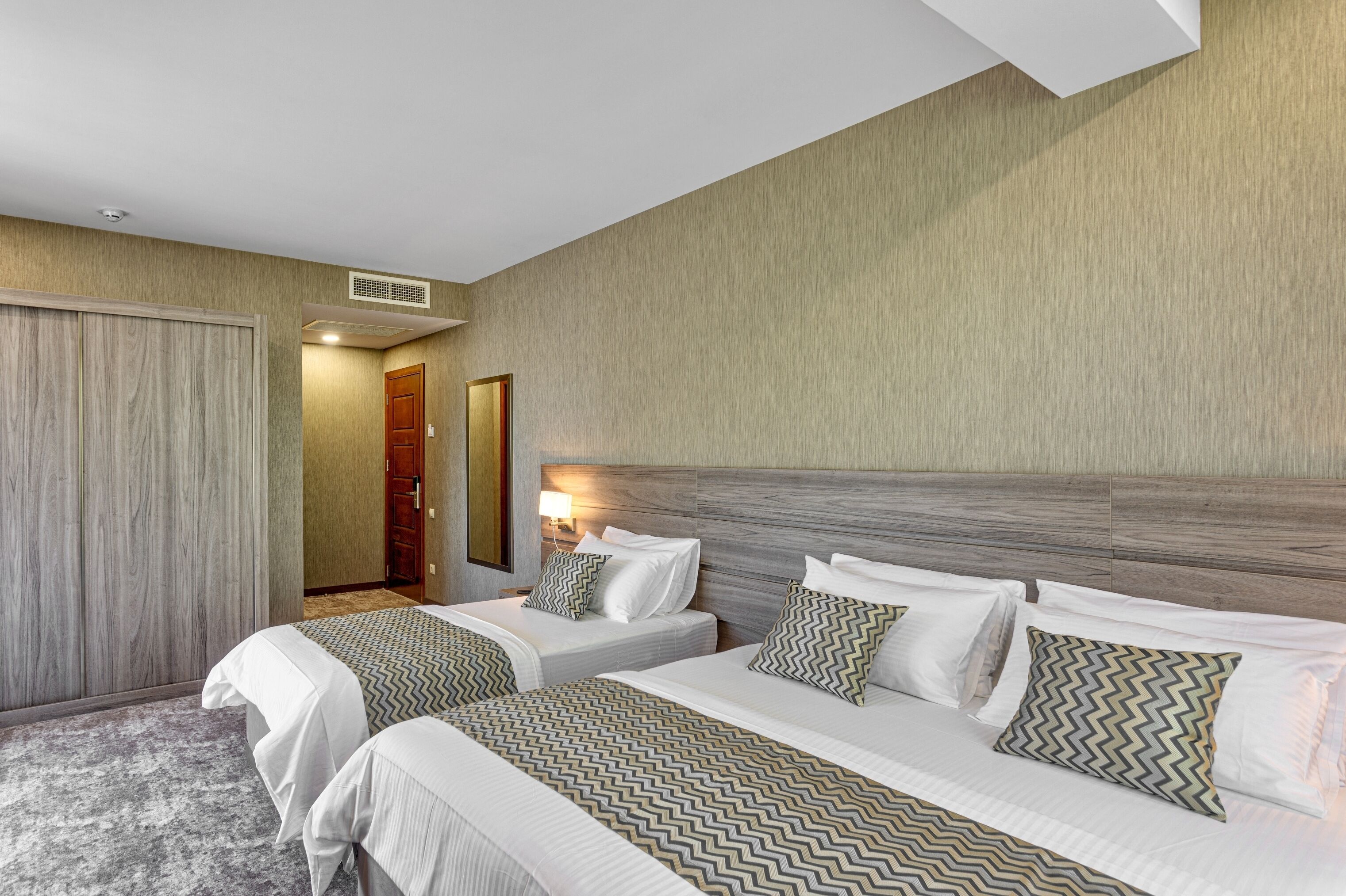 Une chambre d’hôtel avec deux lits, une tête de lit en bois et un sol recouvert de moquette.