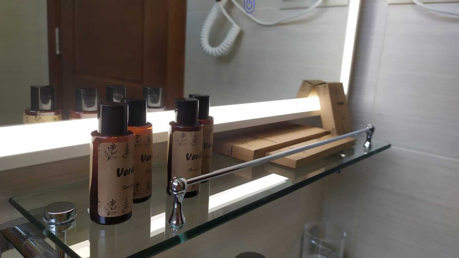 A bathroom with a glass shelf holding bottles and a wooden box.