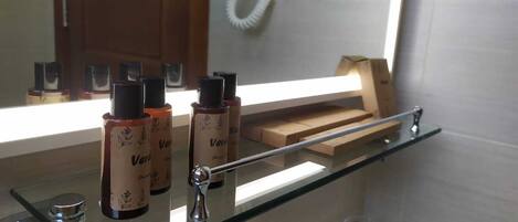 A bathroom with a glass shelf holding bottles and a wooden box.