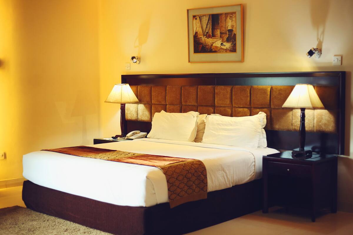 Ein Hotelzimmer mit einem großen Bett, zwei Nachttischlampen, einem Telefon und einem Bild an der Wand.