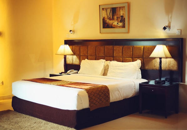 Habitación de hotel con una cama grande, dos lámparas de noche, un teléfono y un cuadro en la pared.
