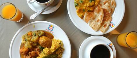 A table with four plates of food, two cups of coffee, and two glasses of orange juice.