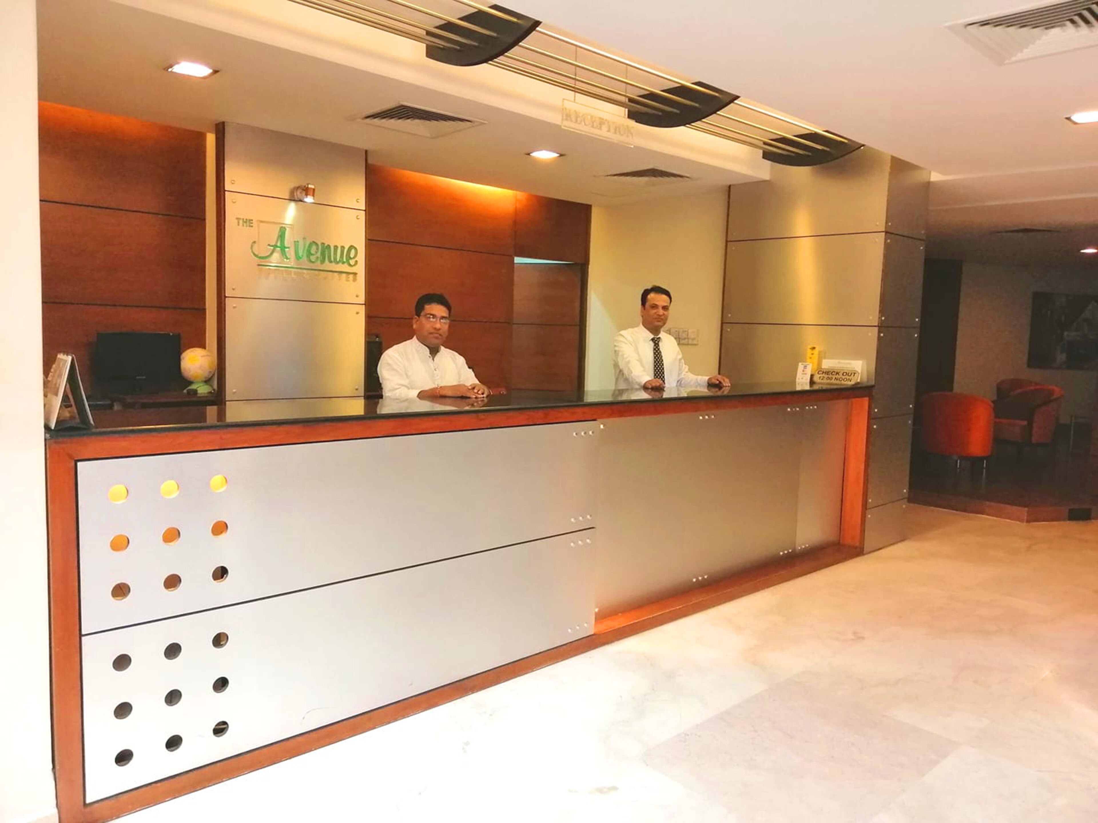 A reception desk with two staff members, a sign reading "The Avenue," and a check-out counter with a sign.