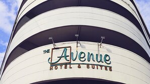 Ein mehrstöckiges Gebäude mit einem Schild, auf dem 'The Avenue Hotel & Suites' steht.