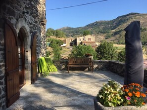 A stone building with arched wooden doors, a bench, and a concrete floor. - Gite du clos long, in a secluded hamlet (Saint-Priest)