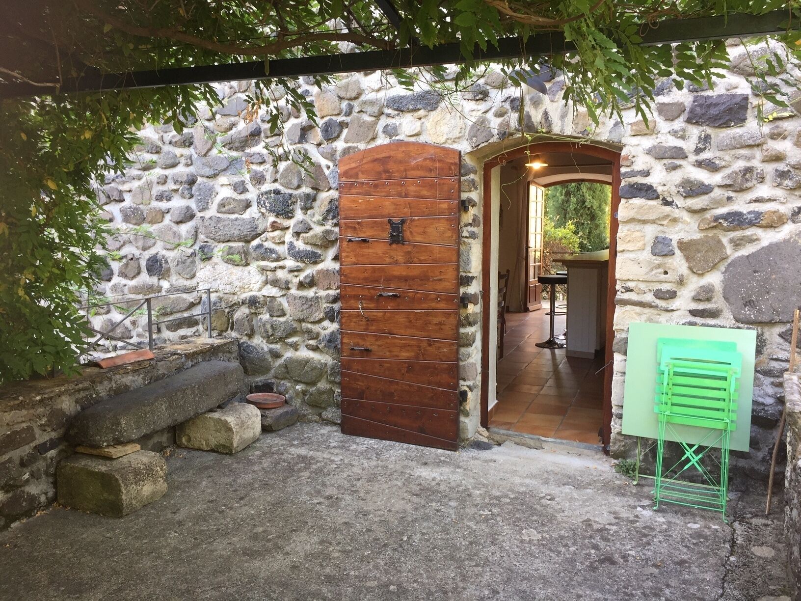 A rustic stone wall with a wooden door and a green drying rack.