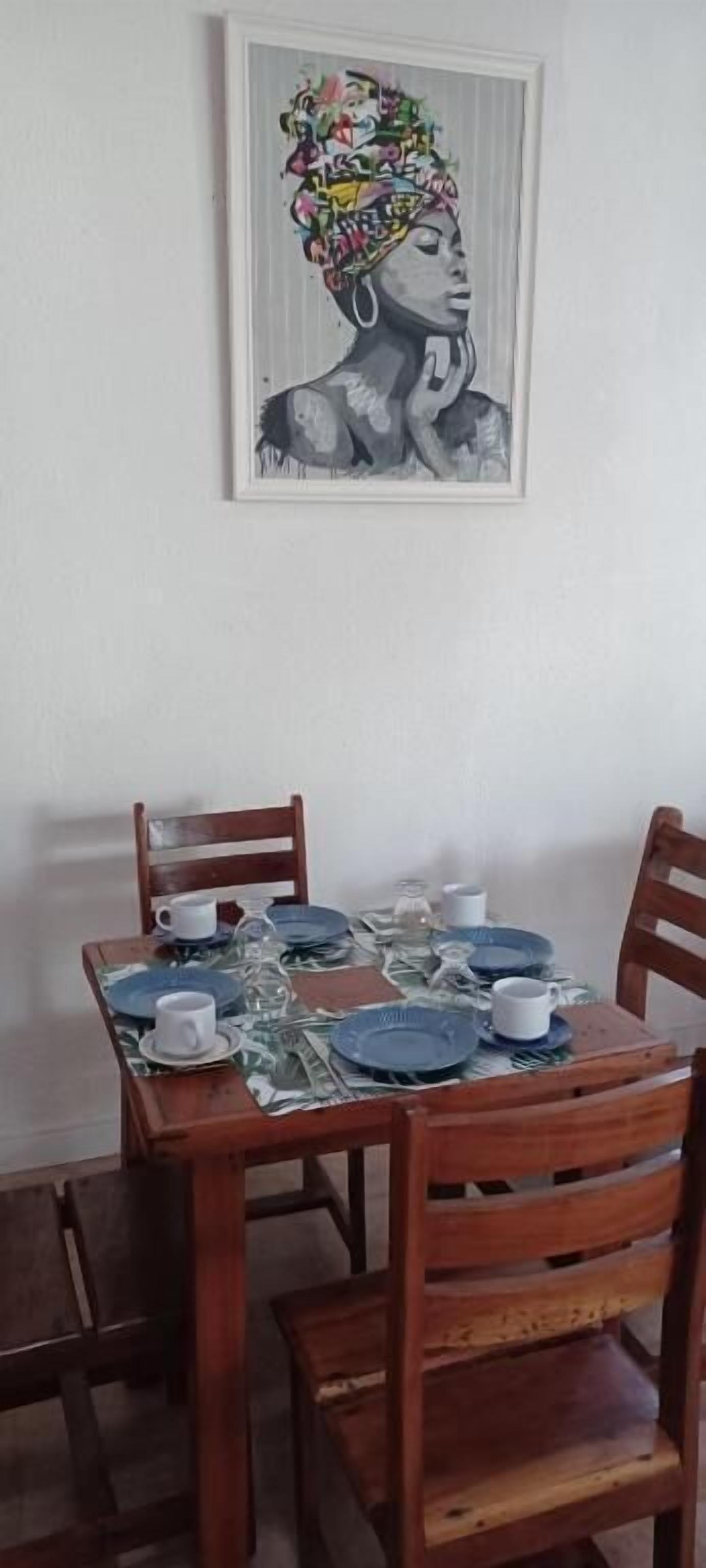 A dining table with a framed artwork above it.