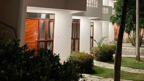 A modern building with a balcony and a well-maintained garden. - Pousada Neptun (Conde)