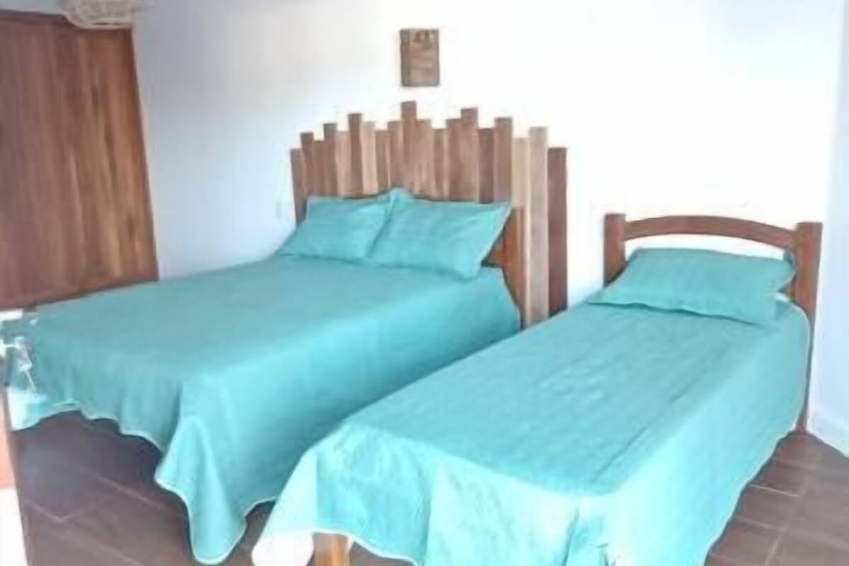 A room with two beds, wooden headboards, and a hanging light fixture.