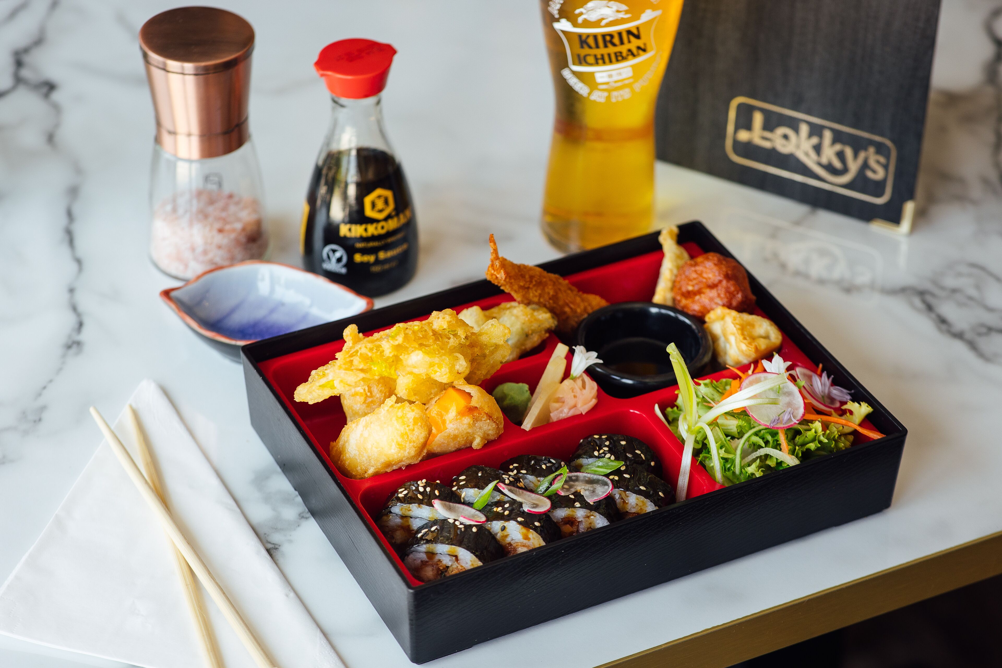 Un repas composé de différents plats, présenté dans une boîte noire sur une table en marbre.