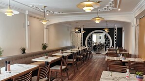 A restaurant with wooden flooring, marble tables, and pendant lighting. - The Imperial Dragon Hotel (Saundersfoot)