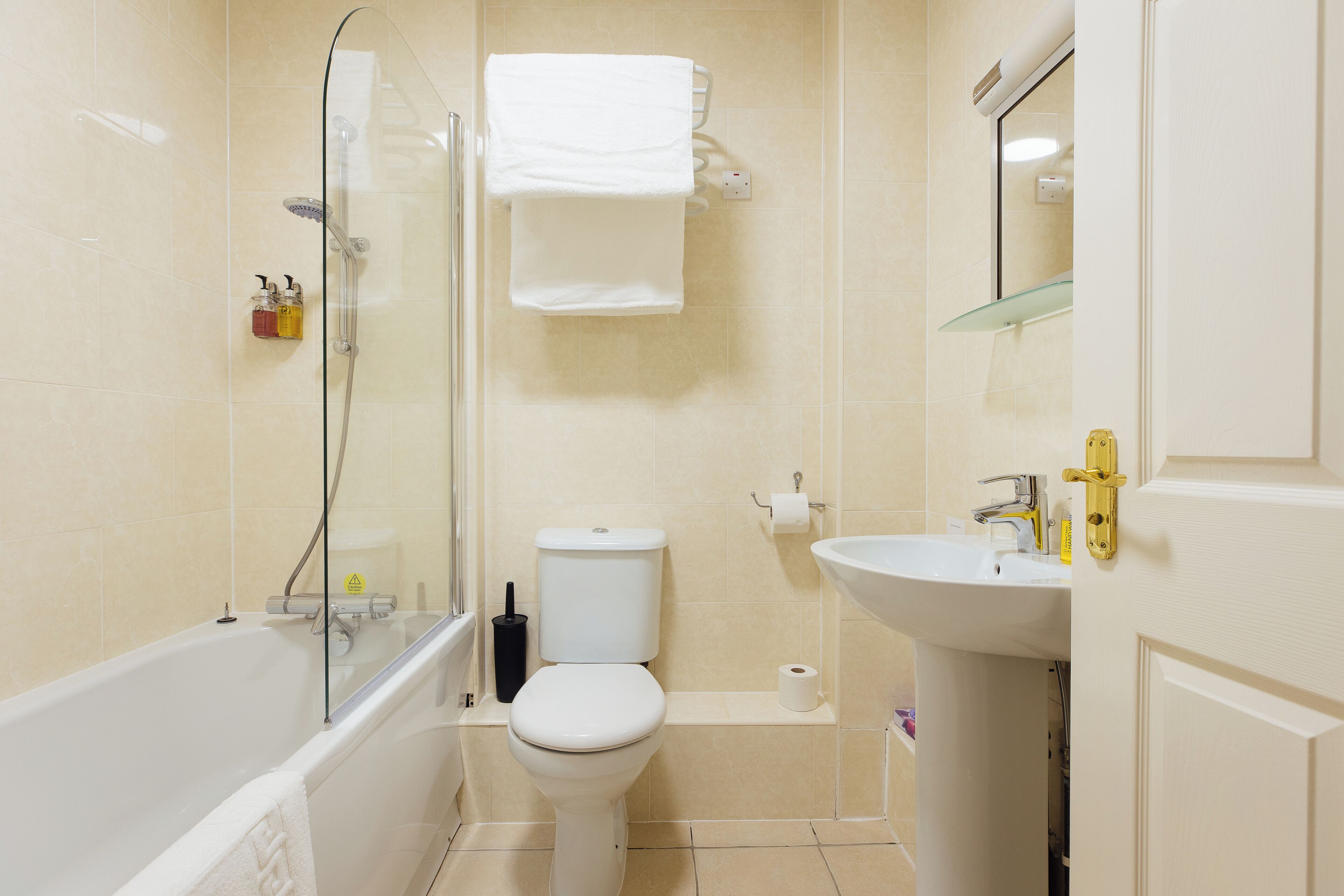A modern bathroom with a glass-enclosed shower, a white toilet, and a sink with a mirror above it.