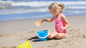 Een kind speelt met zand op het strand.