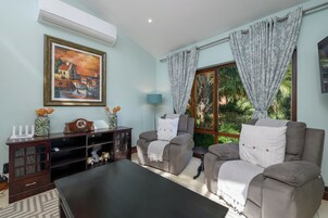 A living room with a sofa, armchairs, a coffee table, a TV, and a painting on the wall.