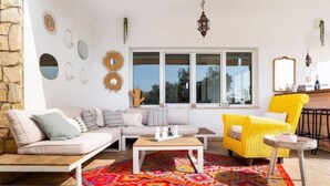 A living room with a sofa, a yellow armchair, a coffee table, and a patterned rug. - Villa Zebra with sea views from every room! (Benalmádena)