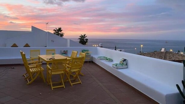 A terrace with yellow chairs and a table, overlooking a beach and the sea during sunset. - Villa Zebra with sea views from every room! (Benalmádena)