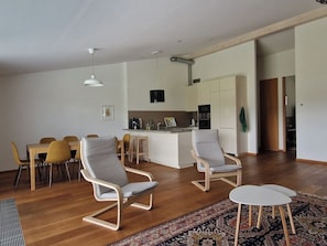 Un salon moderne comprenant un coin repas, une cuisine et un petit îlot central.