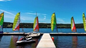 A dock with several sailboats and a jet ski, a clear blue sky, and a calm lake. - Domaine Bleu - Lakefront & Private Beach (Pohénégamook)