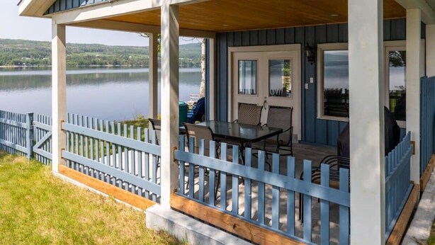 A covered porch with a table and chairs, overlooking a lake. - Domaine Bleu - Lakefront & Private Beach (Pohénégamook)