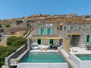 Un bâtiment en pierre doté d’une piscine et d’un espace extérieur aménagé pour s’asseoir.