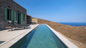 A stone building with a pool extending to a hillside. - Kalma Living - Luxury Villas (Kithnos)