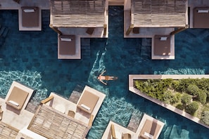 An aerial view of a swimming pool with lounge chairs and a person swimming.