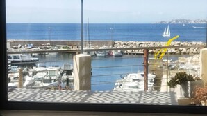 Un porto turistico con imbarcazioni ormeggiate, una frangiflutti rocciosa e una vista aperta sul mare.