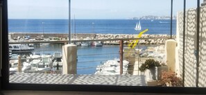 Een jachthaven met aangemeerde boten, een rotsenrijke breekwater en een helder uitzicht op de zee.