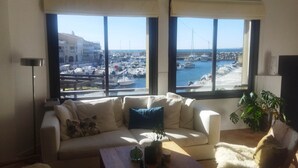 Un soggiorno con una grande finestra che si affaccia su un porto turistico.